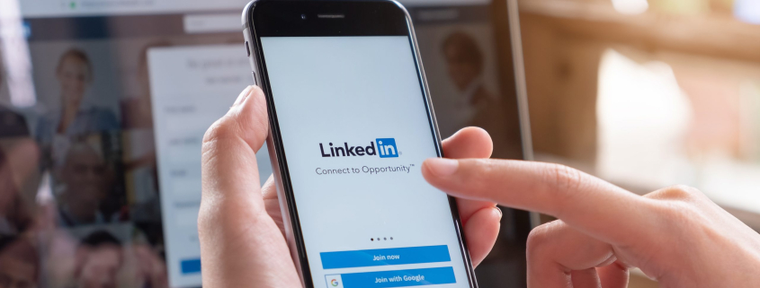 Handy mit der LinkedIn-App vor PC | AUSGEZEICHNET.ORG