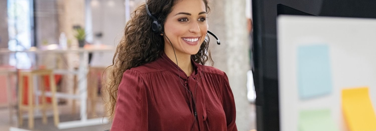 Frau sitzt am Computer mit einem Headset und bietet Kundensupport für mehr Customer Care
