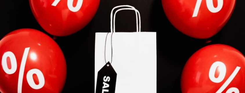 Ausgezeichnet.org spricht darüber, wie Händler sich auf das Angebotswochenende rund um "Black Friday" und Cyber Monday vorbereiten können, auf dem Bild sind eine Shoppingtüte und Ballons zu sehen mit der Aufschrift Sale