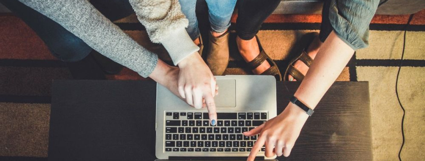 Ausgezeichnet.org zählt die Vorteile von Newsletter-Marketing auf und erklärt, worauf bei einer Mailing-Kampagne geachtet werden muss, das Bild zeigt, wie 3 Personen auf einen Laptop zeigen