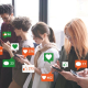 Ausgezeichnet.org erklärt virales Marketing und zeigt auf, wie es dazu kommen kann, das Bild zeigt eine Gruppe von Menschen am Smartphone, aus denen zur Verbildlichung Sprechblasen mit Likes und Kommentare aufsteigen